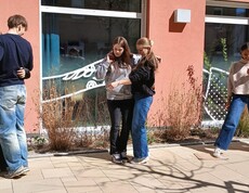 Schülerinnen und Schüler bei einem Teambuilding Spiel. Halten einander fest, stehen auf einem Blatt Papier zu zweit.